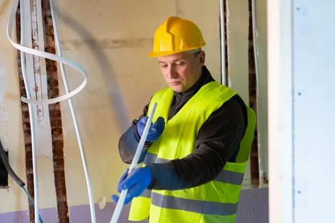 Builder cuts plastic pipe with special interior in house under construction Stock Photos