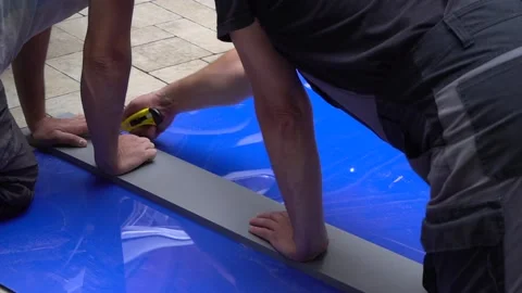 A builder cuts a sheet of blue plastic with a knife. Repair and construction. Stock Footage 148221453