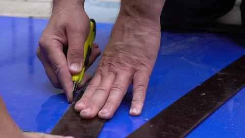 A builder cuts a sheet of blue plastic with a knife. Repair and construction. Stock Footage 148221487