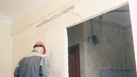 The Builder destroys the plaster on the wall Stock Footage 99789834