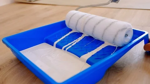 The builder dips the roller in the paint and rolls it along the wall of the tray Stock Footage 117219048