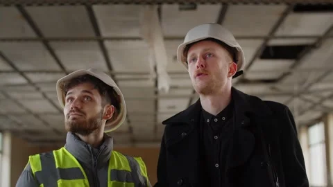 The builder is discussing something with the building inspector. Two men in Stock Footage 236773025