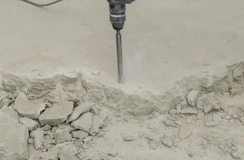 A builder dismantles a perforator drill breaks the concrete floor at a construct Stock Photos