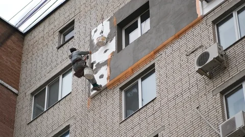 Builder doing insulating work holding on insurance at height. Stock-Footage 117140434