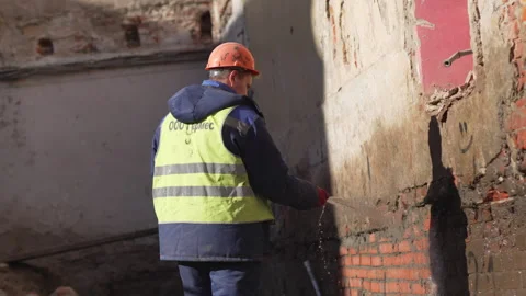 Builder drenches wall with steady stream  from green hose Video stock 314649877