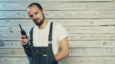Builder with a drill hiding the money in overalls Stock Footage 82976152