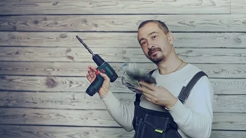 Builder with a drill rejoices earned money Stock Footage 83077009