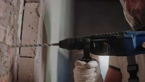 Builder drilling a wall with hammer drill, wearing safety glasses and headphones Vídeo Stock 170501918