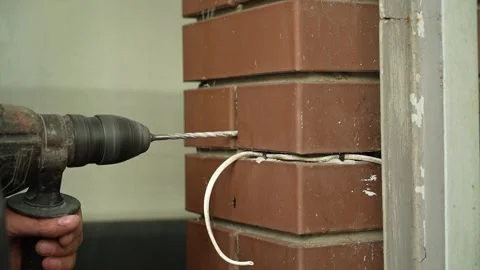 Builder Drills a hole in the wall with a Hammer Drill Stock Footage 258645983