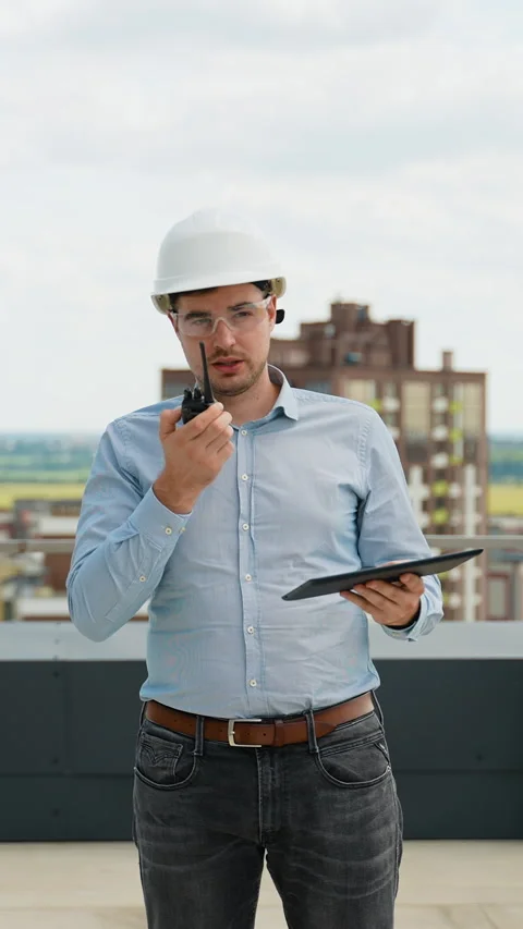A builder engineer on a construction site uses a walkie-talkie and a tablet for Stock Footage 285682891
