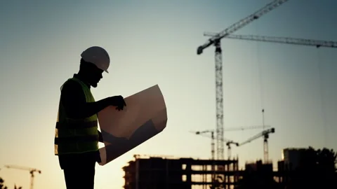 Builder, engineer or architect in helmet checking drawings at construction site Stock Footage 317806587
