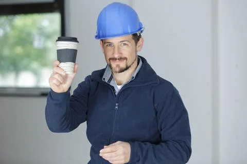 Builder engineer smiles while he holds a cup of coffee Stock Photos