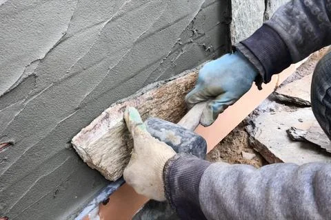 Builder faces the basement of a house with a wild stone. Flat for cladding,.. Stock Photos
