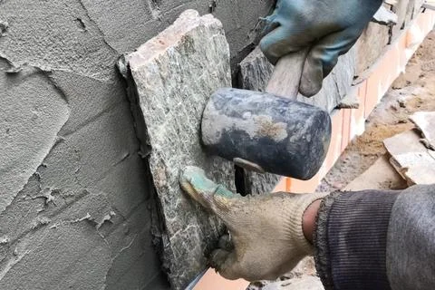 Builder faces the basement of a house with a wild stone. Flat fo Foto stock