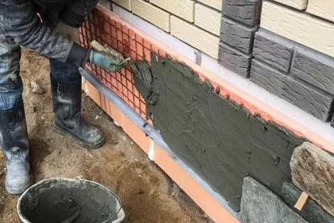 Builder faces the basement of a house with a wild stone. Flat for cladding,.. Stock Photos