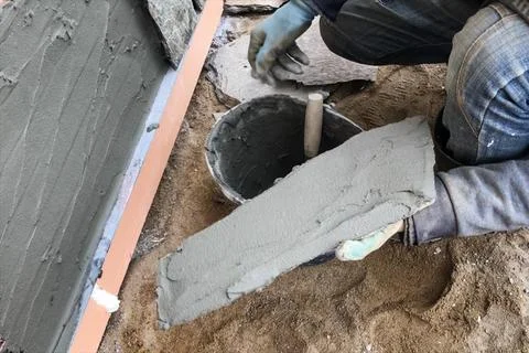 Builder faces the basement of a house with a wild stone. Flat fo Stock Photos
