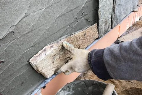 Builder faces the basement of a house with a wild stone. Flat fo 스톡 사진