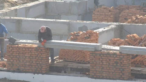 Builder fasten concrete beam on the wall of the house. brick building Stock Footage 120674813