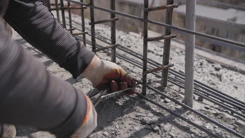 Builder fixes the reinforcement on the construction site with wire Stock Footage 237335619