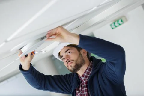 Builder fixing ceiling at the working area indoors Stock Photos