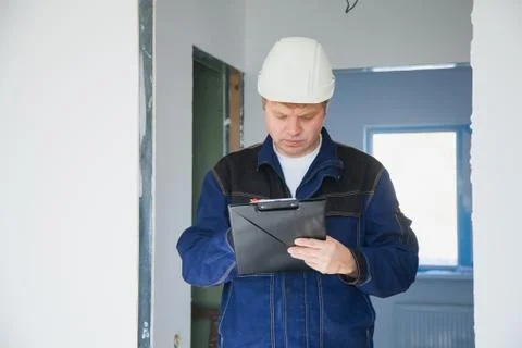 Builder foreman in a white helmet at a construction site indoors Stock Photos