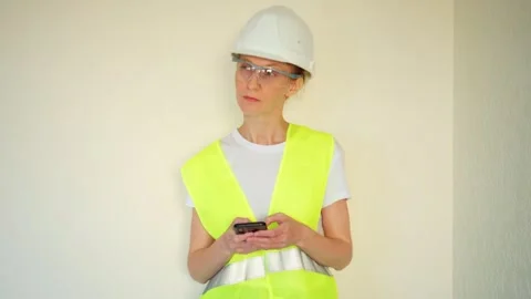 The builder girl thoughtfully looks at examples of the interior in the phone. Video stock 248113846