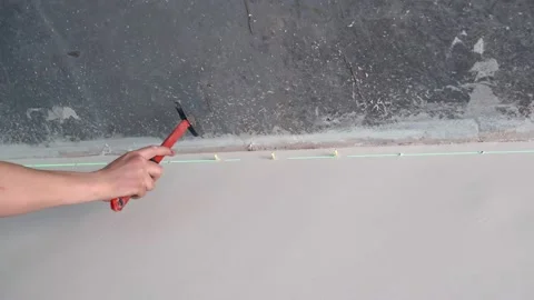 The builder hammers the caps into the holes in the wall with a hammer in Stock Footage 154295710