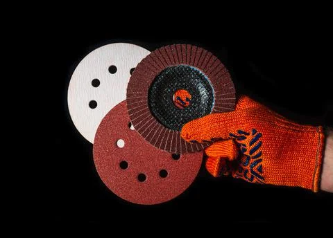 Builder hand in glove keeps or gives abrasive tools close up Stock Photos