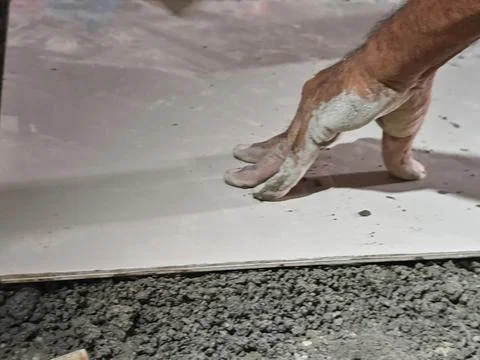 Builder Hand Pressing Ceramic Tile onto Fresh Cement Screed Stock Photos