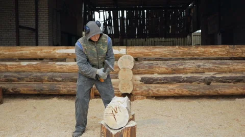 Builder handles wooden timber with axe. Against the background is part of the Stock Footage 69002756