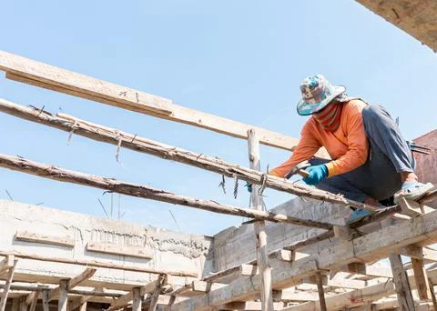 Builder hands hammering a nail into a formwork support second floor . Stock Photos