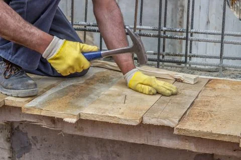 Builder hands hammering a nail into a plank Stock Photos