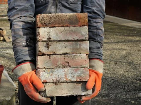 Builder hands holding old bricks Stock Photos