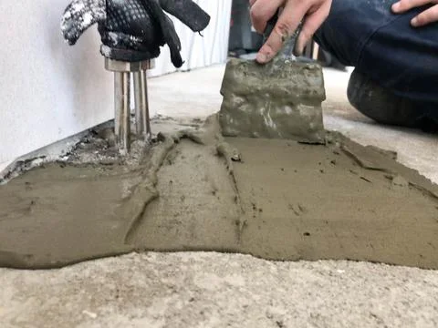 Builder hands with a metal spatula plaster the wall, pours the screed with pl Stock Photos