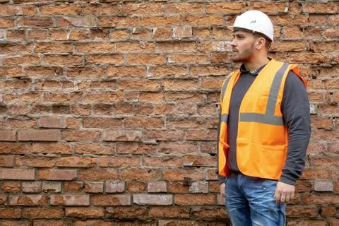 Builder in a hard hat on a brick wall background. Stock Photos