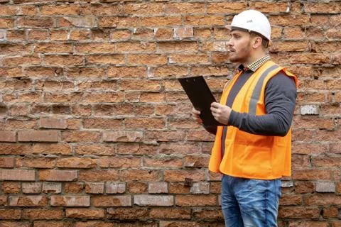 Builder in a hard hat on a brick wall background. Foto stock