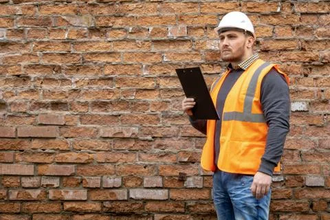 Builder in a hard hat on a brick wall background. Foto stock
