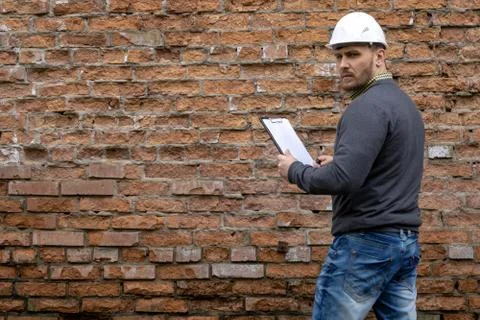 Builder in a hard hat on a brick wall background. Foto stock
