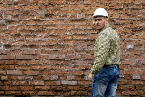 Builder in a hard hat on a brick wall background. Foto stock