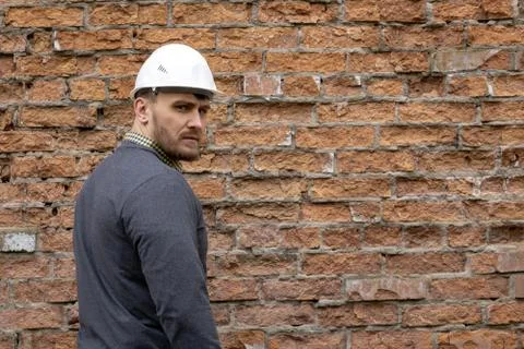 Builder in a hard hat on a brick wall background. Foto stock