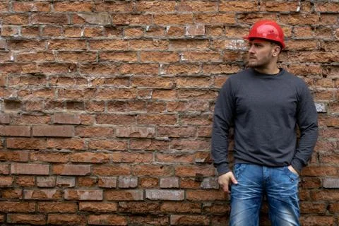 Builder in a hard hat on a brick wall background. Foto stock