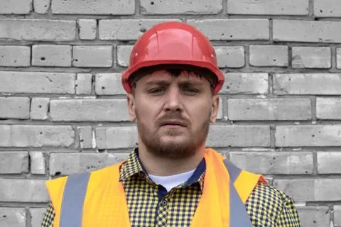 Builder in a hard hat on a brick wall background. Foto stock
