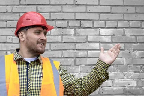 Builder in a hard hat on a brick wall background. Foto stock