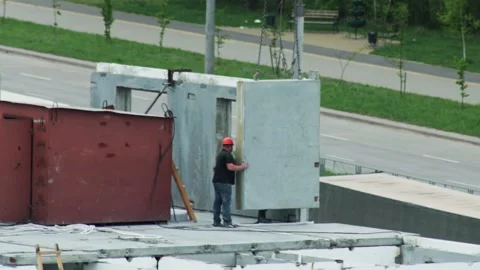 Builder In Hard Hat Guides Concrete Panel. Crane Lowers Prefabricated Wall Into Stock Footage 339865898