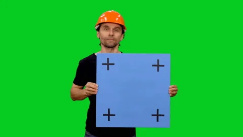 Builder in hard hat holding blank board on green screen Stock Footage 130794534