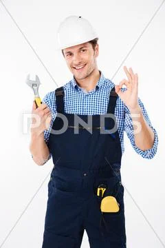 Builder in hard hat holding wrench and showing ok sign Stock Photos