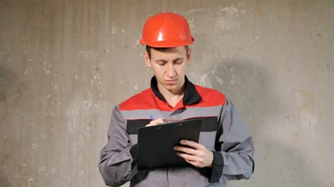 Builder in hardhat writing on clipboard Stock Footage 100056829