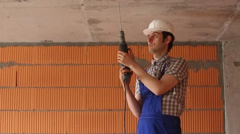 Builder in a helmet is drilling the ceiling Stock Footage 61728113