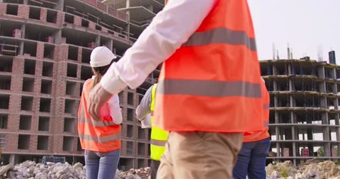 Builder in helmet is standing in front of the construction site, talking by Stock Footage 172287983