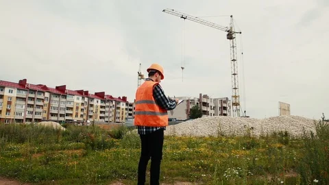 A builder in a helmet stands with his back writing data against the background Video stock 129164028